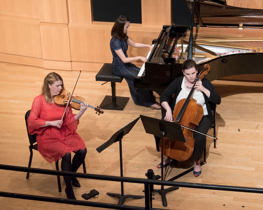 Cello, violin and piano perform on stage