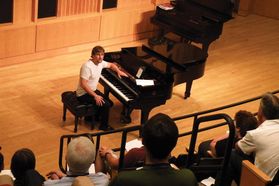 student turns to audience after finishing playing piano